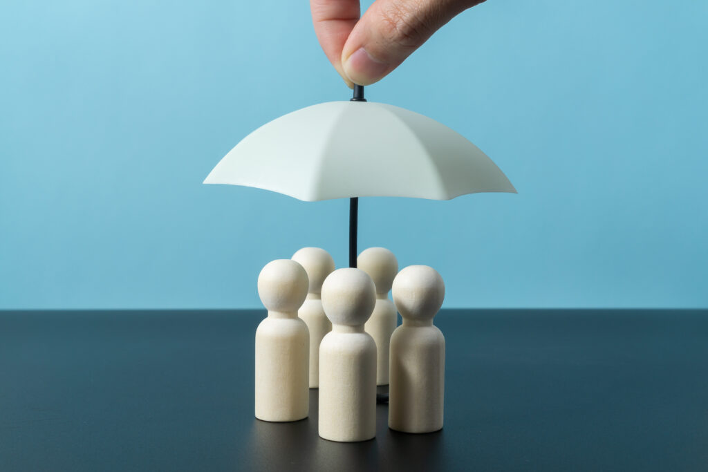 wooden doll figures with toy umbrella insurance coverage concept